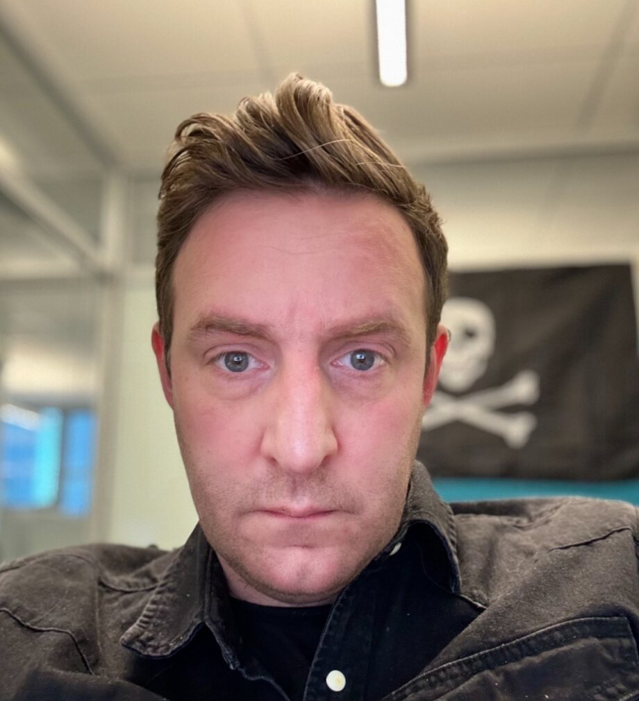 Matt Wood in his office in 2023, with a skull and crossbones flag on the wall behind him